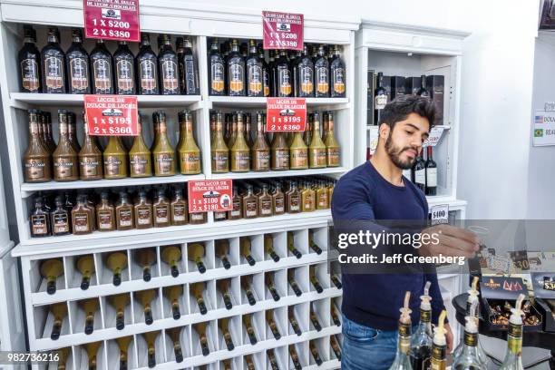 Sales clerk offering free samples of caramel liqueur at La Casa del Dulce de Leche.