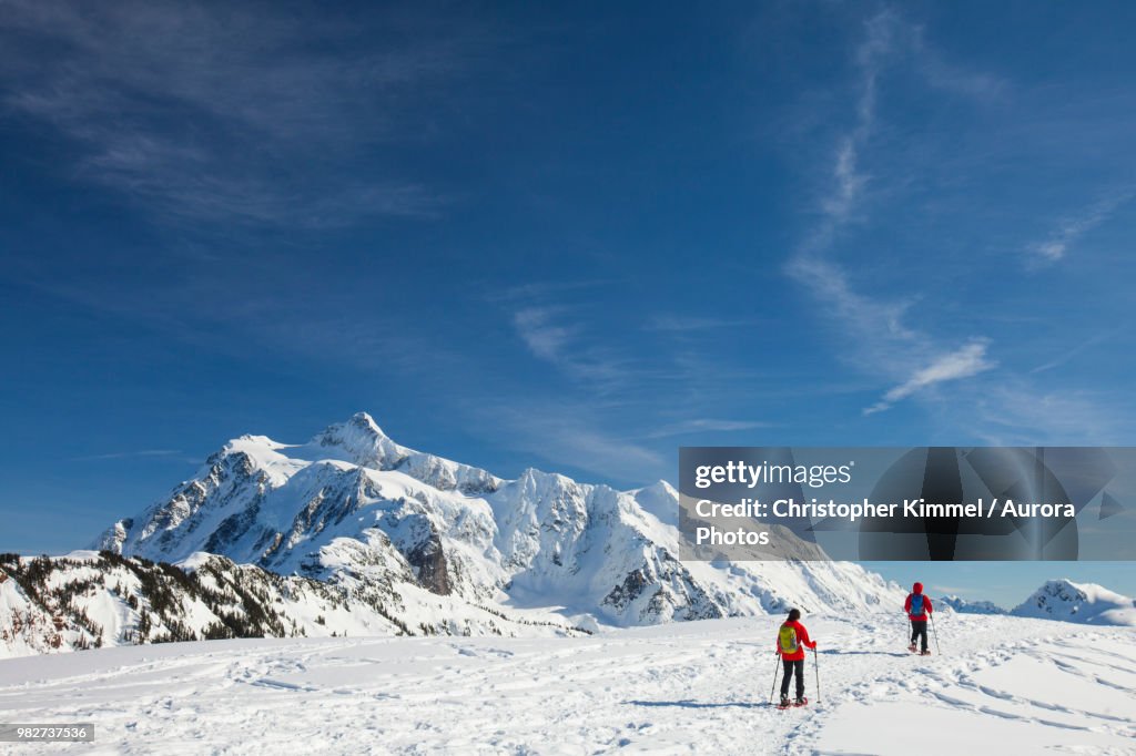 Two people snowshoeing below Mount Shuksan in winter, North Cascades National Park, Washington State, USA