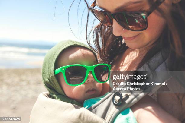 mother holding baby son at beach - diaper bag stockfoto's en -beelden
