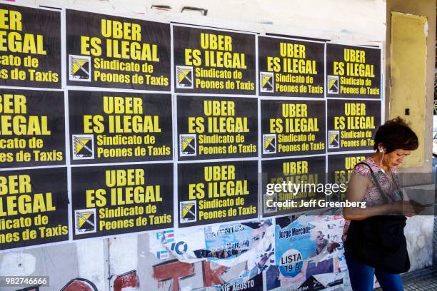 Argentina, Buenos Aires, woman using smartphone with Taxi Union posters behind.