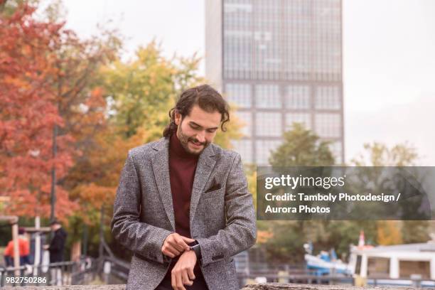 hispanic male using smartwatch in street - mens wrist watch stock-fotos und bilder