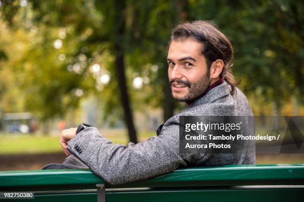 portrait of businessman in blazer sitting on bench in park - looking back stock pictures, royalty-free photos & images