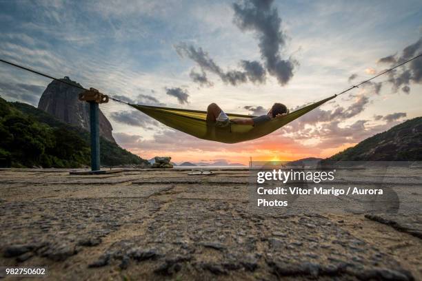 man in hammock at sunrise in rio de janeiro, brazil - praia vermelha rio de janeiro stock pictures, royalty-free photos & images