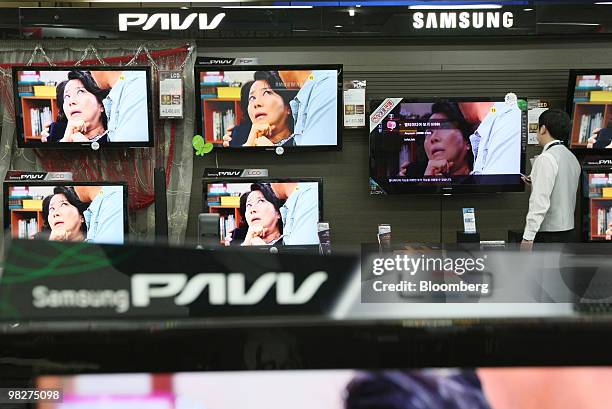 Sales clerk looks at liquid-crystal display and light emitting diodes televisions at Samsung Electronics Co.'s store in Seoul, South Korea, on...