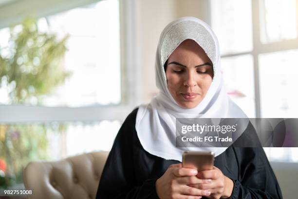 muslim woman using mobile at home - pakistani stock pictures, royalty-free photos & images