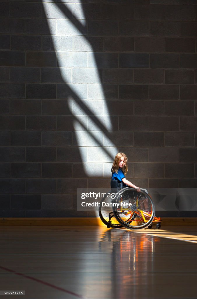 Girl (8-9) on wheelchair in gym