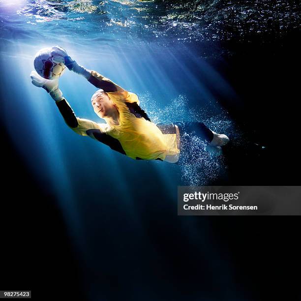 adult goalkeeper catching ball underwater - henrik sorensen stock-fotos und bilder