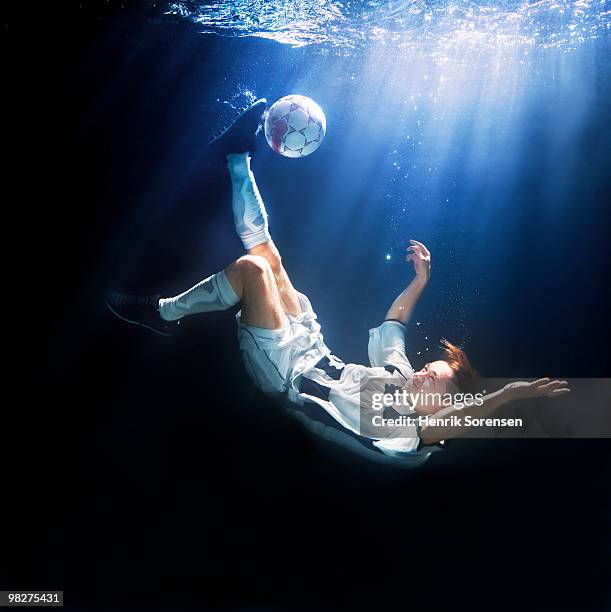 male soccer player kicking ball underwater - henrik sorensen stock-fotos und bilder