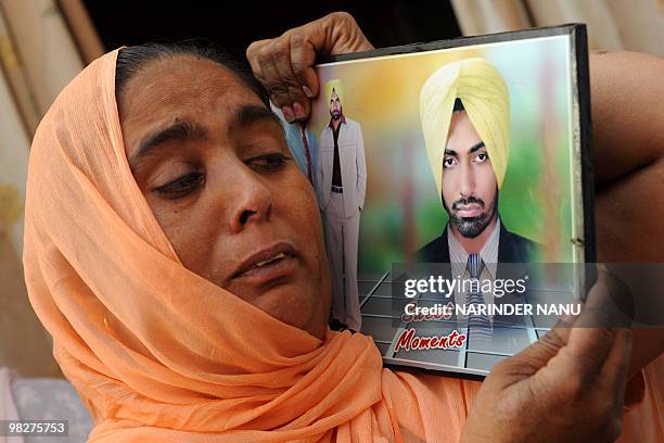 Indian women Veer Kaur holds a photograph of her son Sukhjinder Singh, who was sentenced to death in the United Arab Emirates, in the village of...