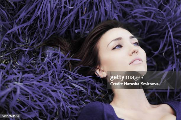 headshot of woman lying down in purple grass - down blouse stockfoto's en -beelden