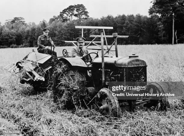 Two Soldiers, Released for Temporary Emergency Farm Work, Operating Tractor and Harvester to cut Ten-Acre Field of Oats during Crop Season, which...