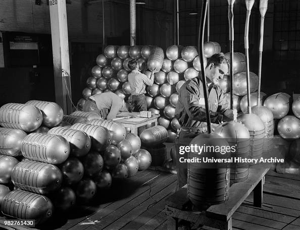 Three Workers Testing and Stacking Shatterproof Oxygen Cylinders for High Altitude Flying Manufactured at Factory Converted to War Production, February 1942 Three Workers Testing and Stacking Shatterproof Oxygen Cylinders for High Altitude Flying Manufactured at Factory Converted to War Production, February 1942