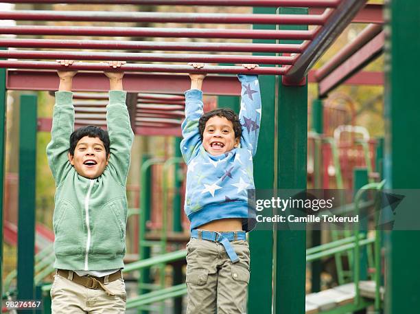 brothers playing on monkey bars at playground. - monkey bars fotografías e imágenes de stock