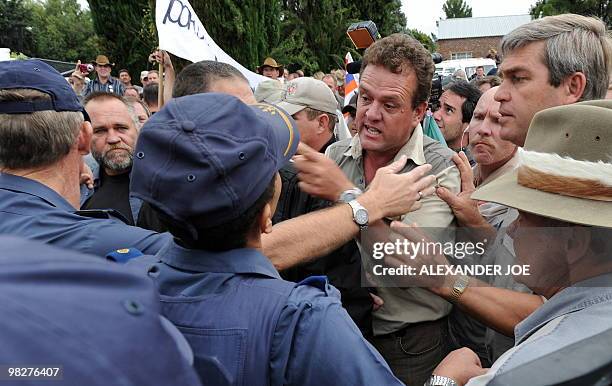 South African police try to keep blacks and whites apart as race tensions flared when a white woman sprayed water as blacks sang the national anthem...