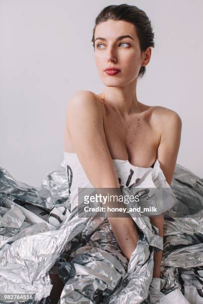woman wearing a paper dress sitting on silver foil - strapless evening gown foto e immagini stock