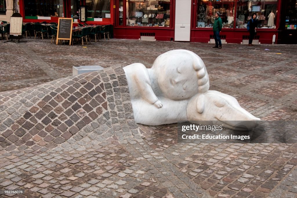 Figures if child and dog sleep soundly under pavement in a square, Antwerp, Belgium