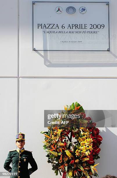 An Italian policewoman of the Guardia di Finanza stands guard near the plate at the military academy of Coppito, marking the first anniversary of the...