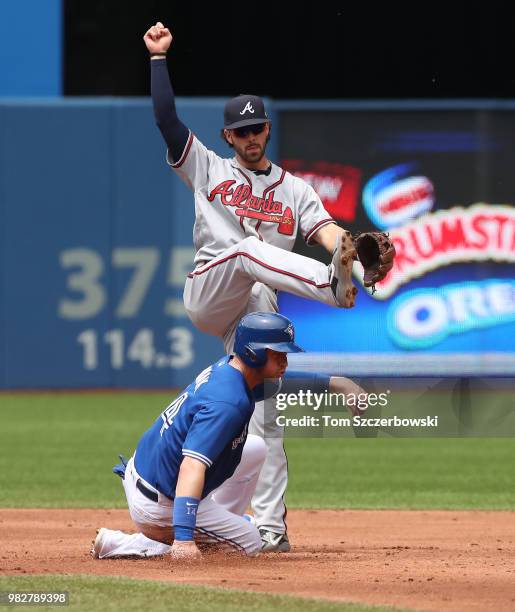 Dansby Swanson of the Atlanta Braves turns a double play in the third inning during MLB game action as Justin Smoak of the Toronto Blue Jays slides...