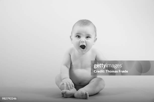 studio shot of baby boy (2-5 months) sitting and pulling funny face - funny baby face stock pictures, royalty-free photos & images