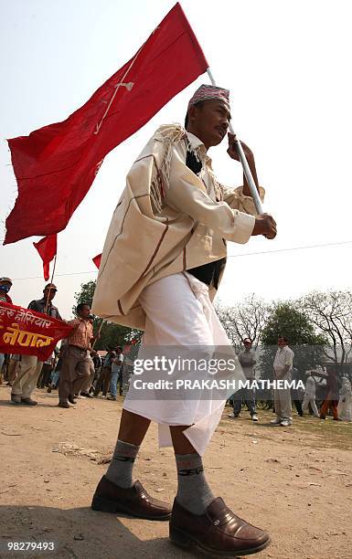 Unified Communist Party of Nepal supporter carries a flag at a mass meeting to mark the anniversary of the 2006 people's uprising in Kathmandu on...