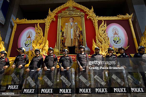 Police stand guard by a portrait of the Thai King wtching as thousands of Red shirt supporters of former PM Thaksin Shinawatra defy the government...