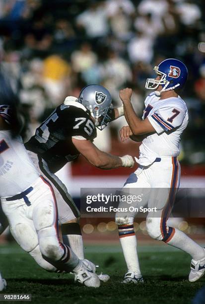 S: Defensive Tackle Howie Long of the Los Angeles Raiders goes after quarterback John Elway of the Denver Broncos circa mid 1980's during an NFL...