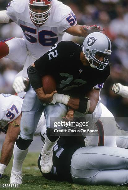 Running Back Marcus Allen of the Los Angeles Raiders plays tries to run through the tackle of a Buffalo Bills defender October 11, 1992 during an NFL...