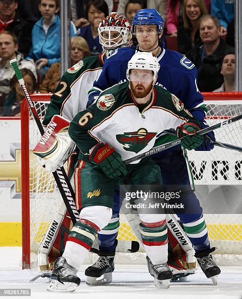 Michael Grabner of the Vancouver Canucks stands between Niklas Backstrom and Greg Zanon of the Minnesota Wild during their game at General Motors...