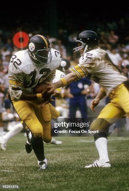 Running back Franco Harris of the Pittsburgh Steelers plays takes a hand off from quarterback Terry Bradshaw circa 1972 during an NFL football game....