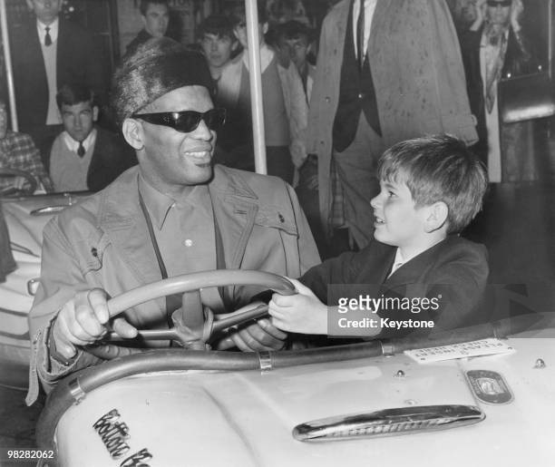 American singer and musician Ray Charles films a scene for 'Ballad in Blue' with young co-star Piers Bishop, on the bumper cars at the Festival...