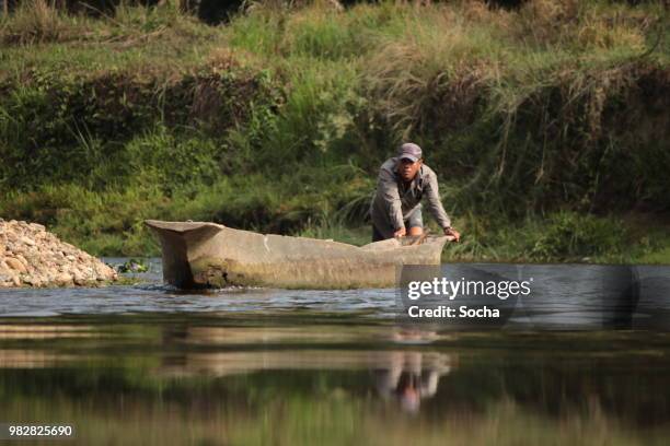 チトワン国立公園のラプティ川のボートで旅ネパールのローカル男 - dugout canoe ストックフォトと画像