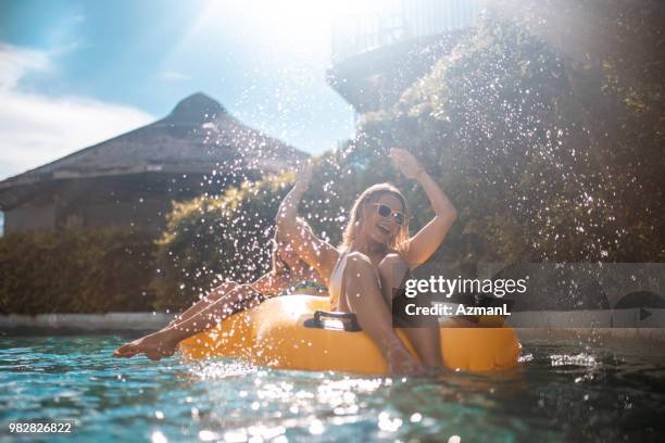 sisters enjoying on inflatable ring at park - woman activity stock pictures, royalty-free photos & images
