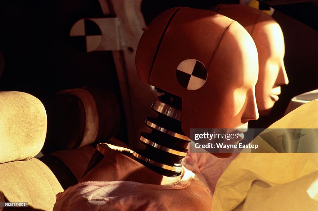 Crash-test dummies inside car with inflated airbags, close-up