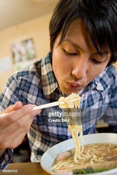 young man eating ramen noodles - eating ramen noodles stock pictures, royalty-free photos & images
