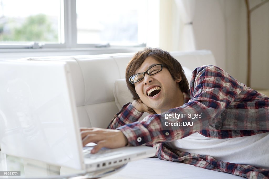 Young man lying on bed using laptop