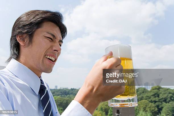 mid adult man holding beer outdoors - beer bottle mouth stock-fotos und bilder