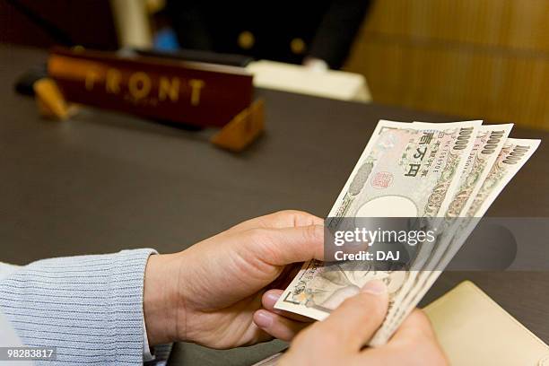 man at the reception in the hotel, holding yen bills, close up - ten thousand yen note ストックフォトと画像