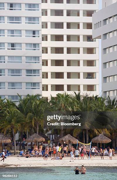 Hotels stand behind tourists on a beach in Cancun, Mexico, on Saturday, April 3, 2010. Passenger traffic at the Cancun airport increased 1.1 percent...