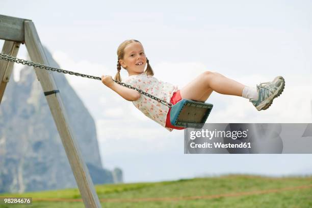 italy, seiseralm, girl (6-7) sitting on swing, portrait - schaukel stock-fotos und bilder