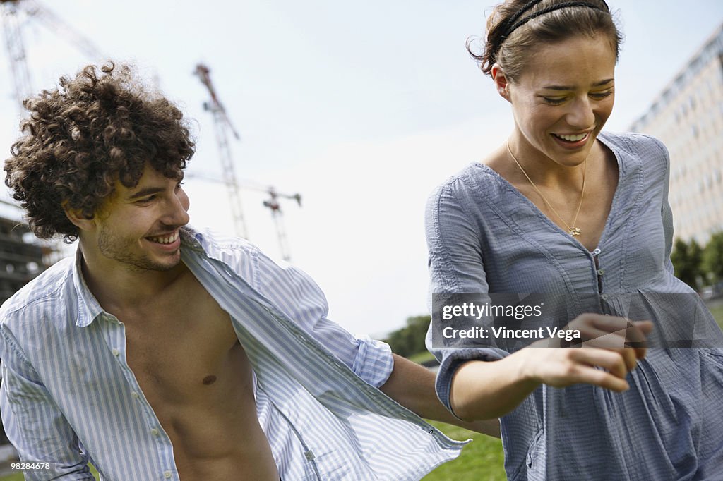 Germany, Berlin, Young couple walking side by side, laughing, portrait
