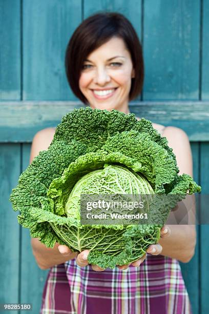 germany, bavaria, woman holding savoy cabbage, smiling, portrait - cabbage family - fotografias e filmes do acervo