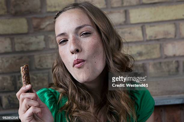 germany, berlin, young woman holding chocolate bar, portrait - indulgence photos et images de collection