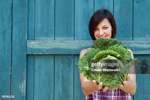 germany, bavaria, woman holding savoy cabbage, smiling, portrait - savoykål bildbanksfoton och bilder