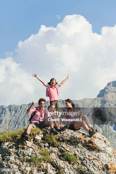 italy, south tyrol, family sitting on rock, cheering, portrait - front view portrait of four children sitting on rock stock-fotos und bilder