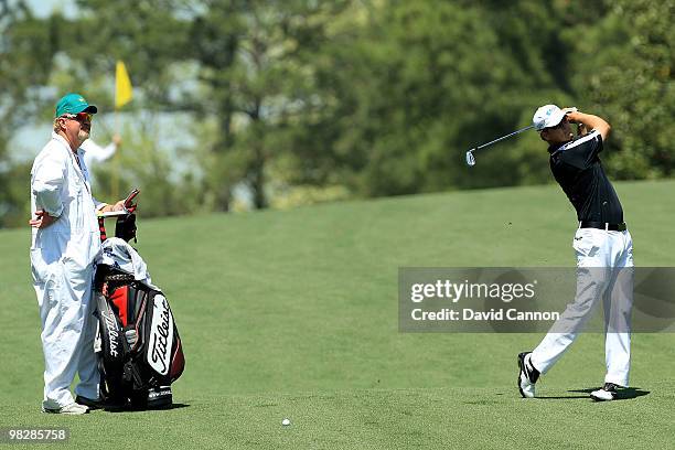 Zach Johnson hits a shot as his caddie Damon Green looks on during a practice round prior to the 2010 Masters Tournament at Augusta National Golf...