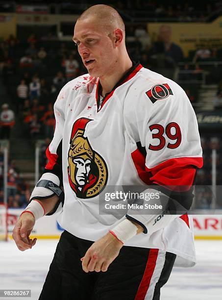 Matt Carkner of the Ottawa Senators is escorted off the ice after being injured during a fight with Trevor Gillies of the New York Islanders on April...