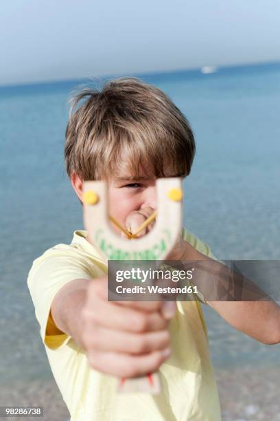 spain, mallorca, boy (8-9) using sling-shot - sling shot stock pictures, royalty-free photos & images