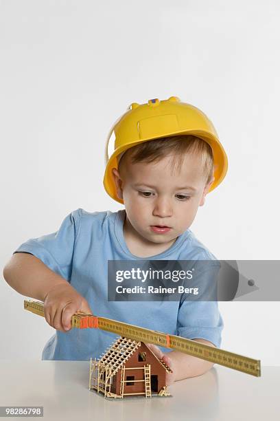 boy (2-3) wearing hard hat, playing with folding rule - boy in hard hat photos et images de collection
