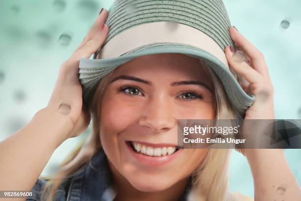 woman holding her hat in the rain - rain hat stock pictures, royalty-free photos & images