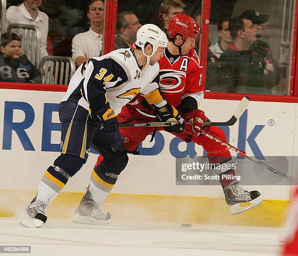 Rod Brind'Amour of the Carolina Hurricanes battles for the puck along the boards with Chris Butler of the Buffalo Sabres during the NHL game on March...